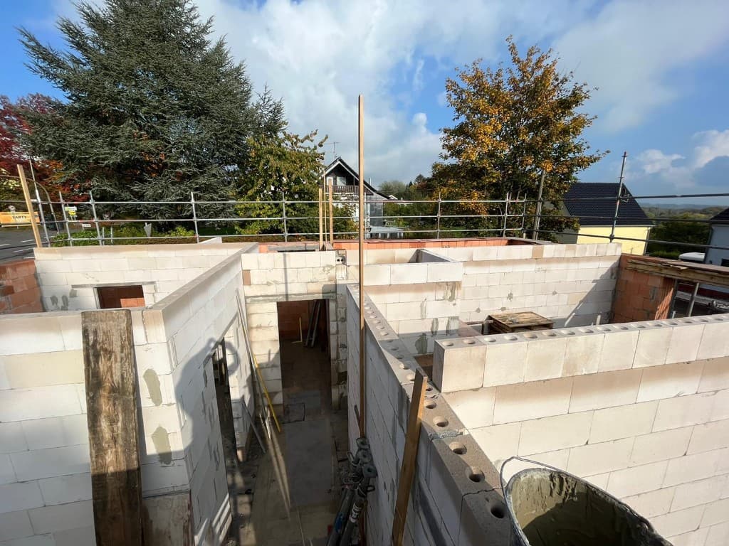 Fundamentarbeiten auf einer Baustelle mit frisch gegossener Betonplatte und Holzschalung