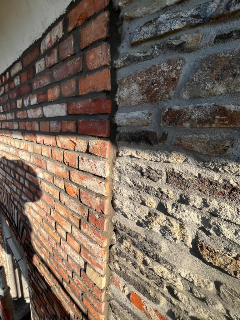 Neue Ziegelfassade mit Fensterbögen und Gerüst an einem Einfamilienhaus