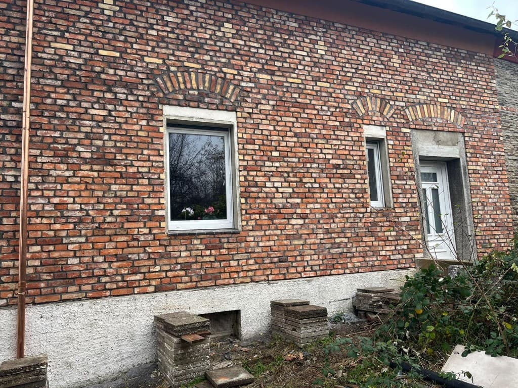 Glasbau mit blauem Rahmen und Natursteinmauern im Garten