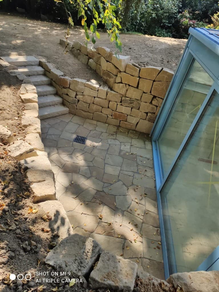 Fassade mit neuer Ziegelwand und Natursteinmauerwerk im Wohngebiet